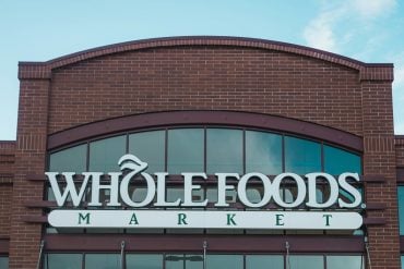 The Whole Foods Market storefront sign and arched brick facade against a blue sky