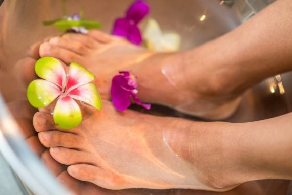 Feet soaking in warm water in a spa-style foot bath