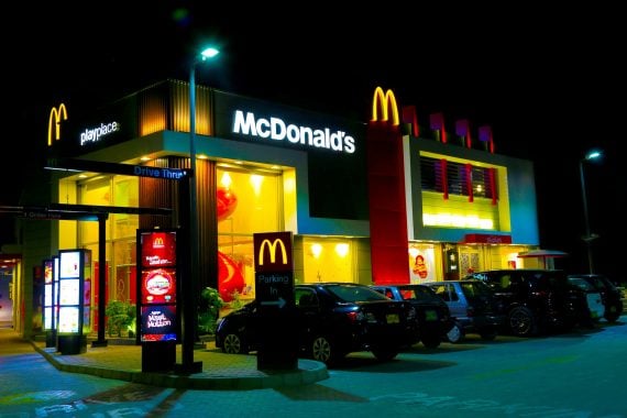A brightly lit McDonald's restaurant at night with glowing golden arches, drive-thru and parking lot — from our ranking of all 12,987 U.S. locations by foot traffic