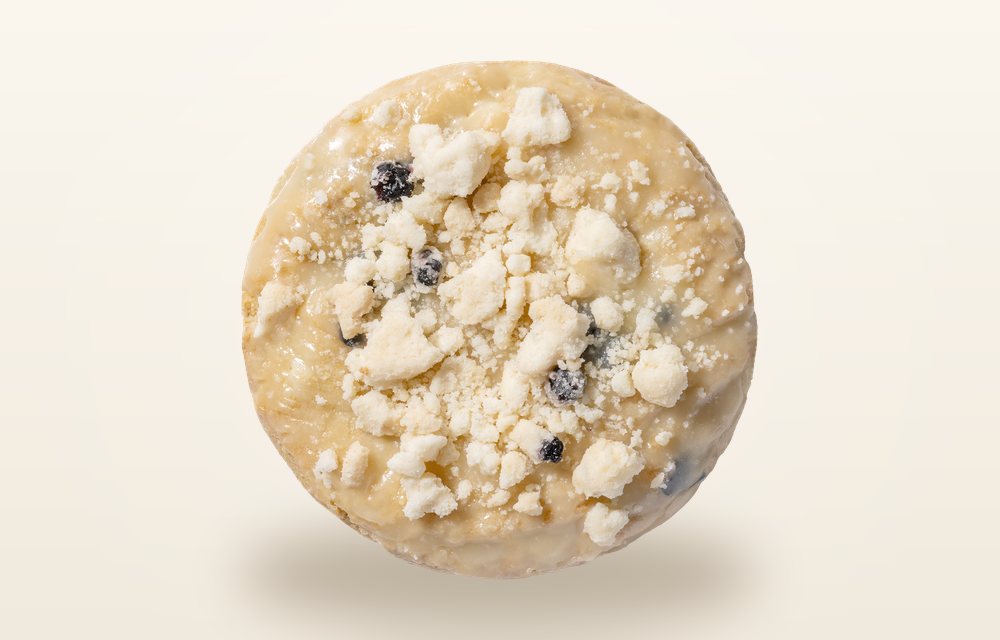 Overhead view of a Crumbl Blueberry Muffin cookie scattered with streusel crumbs and blueberries