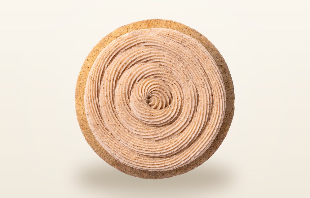Overhead view of a Crumbl Churro cookie piped with a tight spiral of cinnamon buttercream and dusted with cinnamon sugar