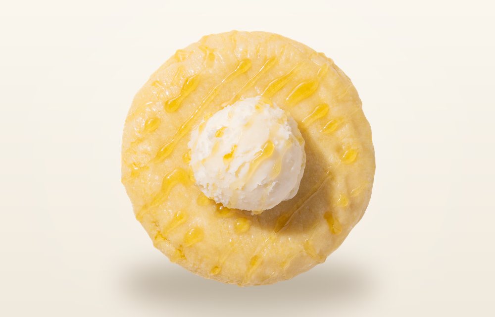 Overhead view of a Crumbl Cornbread cookie glazed with honey butter and topped with a dollop of honey buttercream