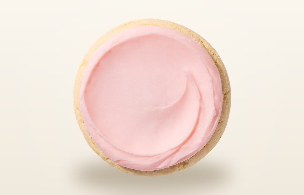 Overhead view of a Crumbl Pink Sugar cookie, a pale sugar cookie spread edge to edge with pink almond frosting