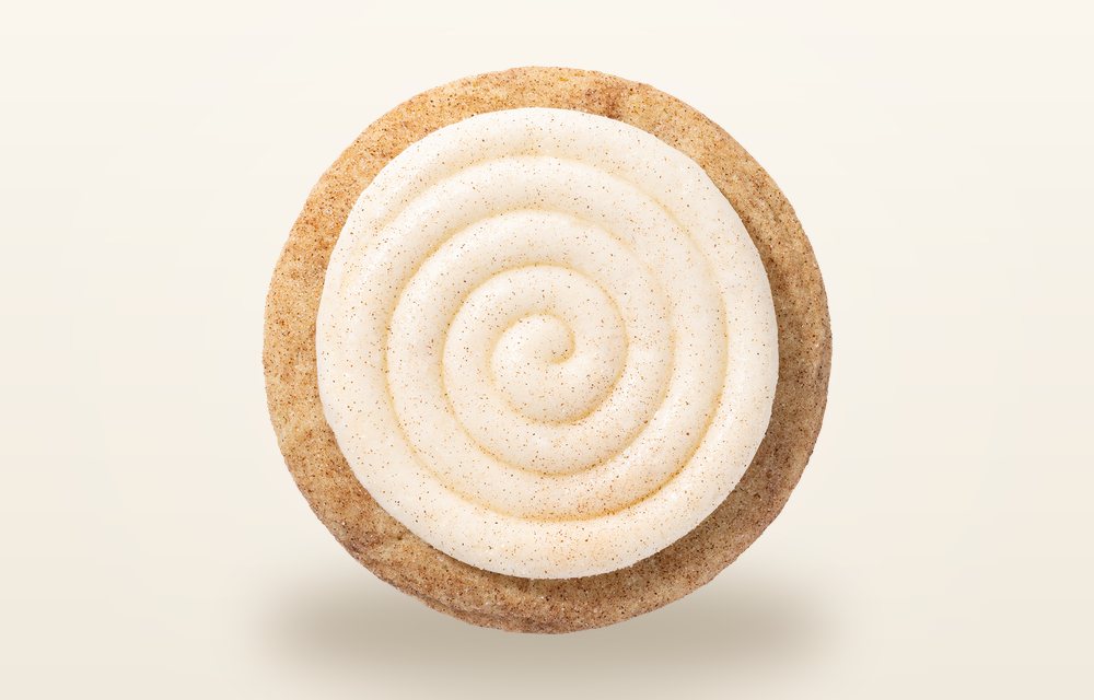 Overhead view of a Crumbl Snickerdoodle Cupcake cookie, a cinnamon sugar cookie under a thick swirl of cream cheese frosting
