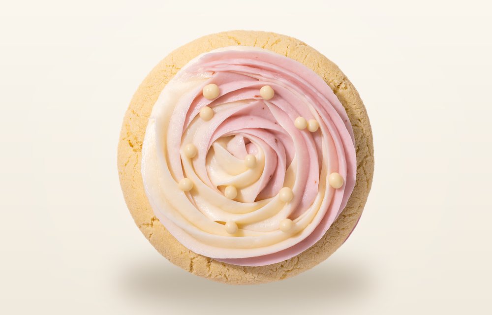 Overhead view of a Crumbl Wedding Cake cookie piped with a spiral of pale almond buttercream