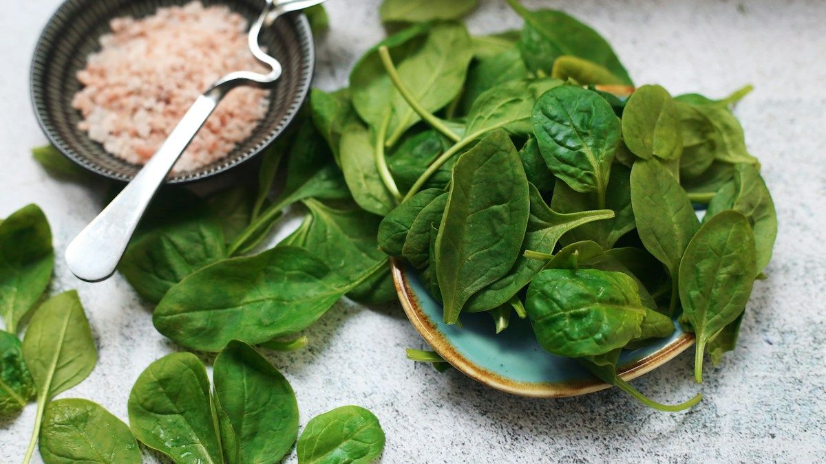 Fresh spinach leaves on a plate, one of the dark leafy greens.
