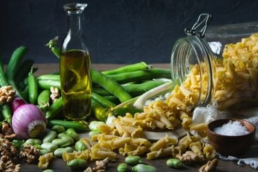 A Mediterranean table of olive oil, beans, pasta, walnuts and fresh vegetables