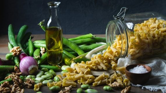 A Mediterranean table of olive oil, beans, pasta, walnuts and fresh vegetables