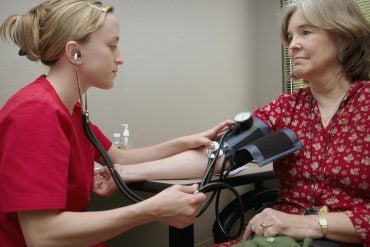 A nurse checking an older woman's blood pressure at a clinic visit