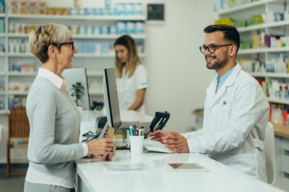 An older woman talking with a pharmacist at a pharmacy counter