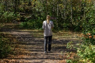 A woman walking a path through autumn woods