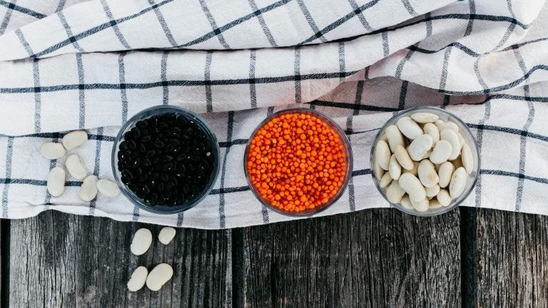 Bowls of black beans, red lentils and butter beans on a checked cloth