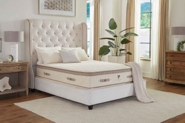 The PlushBeds Luxury Bliss hybrid latex mattress on a tufted bed