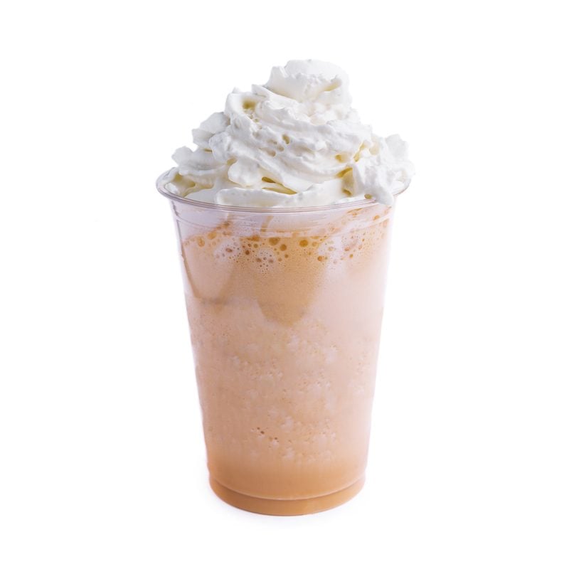 A thick milkshake topped with whipped cream in a clear takeout cup