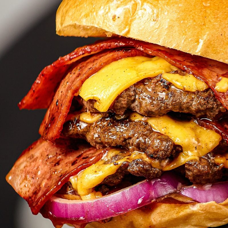 A close-up of a triple bacon cheeseburger with melted cheese and thick-cut bacon
